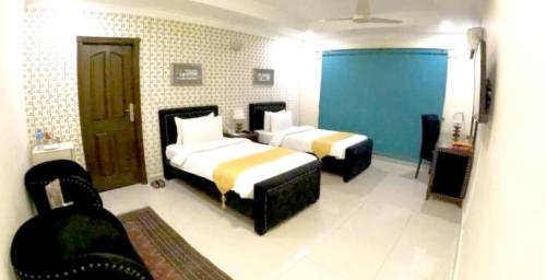 a hotel room with two beds and a chair at Grace Boutique Hotel in Islamabad