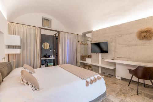 una camera con un grande letto bianco e una TV di Arya Nobile Dimora By Raro Villas a Carovigno