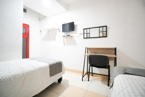 1 dormitorio con 2 camas, escritorio y silla en Griya Sawamah Syariah Mitra RedDoorz, en Yakarta