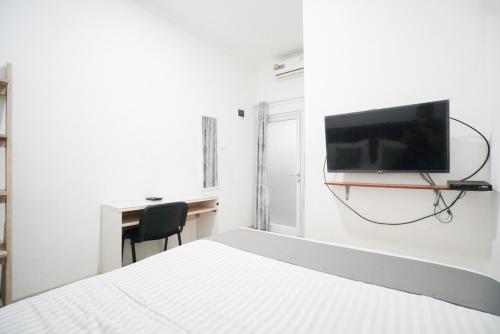 1 dormitorio con 1 cama y TV en la pared en Griya Sawamah Syariah Mitra RedDoorz, en Yakarta