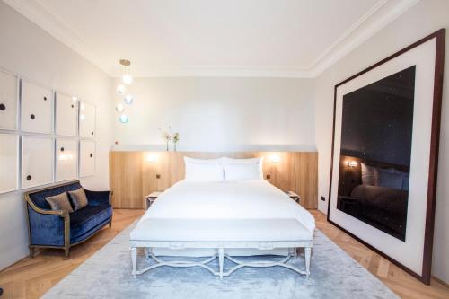 a bedroom with a large white bed and a blue chair at Domaine des Etangs, Auberge Collection in Massignac