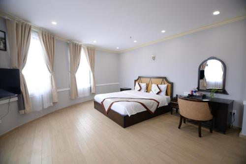 a bedroom with a bed and a desk and a mirror at Quê Tôi Hotel in Soc Trang