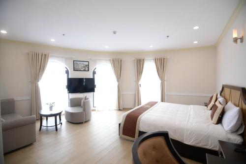 a bedroom with a bed and a chair and a desk at Quê Tôi Hotel in Soc Trang
