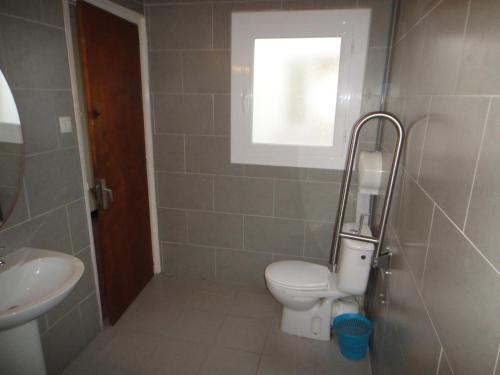 een badkamer met een toilet, een wastafel en een raam bij Pensió Restaurant Llança in Llança