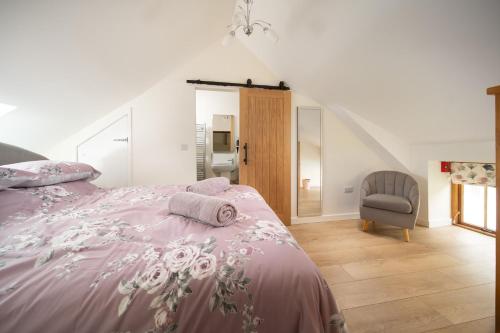 a bedroom with a pink bed and a chair at Orchard View in Stoke Rivers