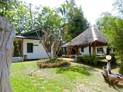 a small house with a thatch roof and a yard at AURA Park Resort in Ban Thung Sam Sao