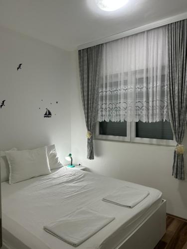 a white bed in a bedroom with a window at Adam's Apartment 2 in Kladovo