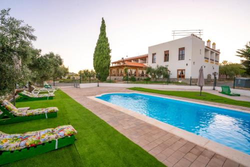 a swimming pool with lawn chairs and a house at Hotel Rural Familiar Almirez-Alpujarra in Laujar de Andarax