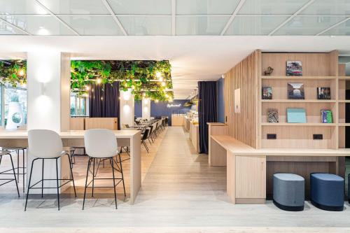 a dining room with tables and stools at Holiday Inn Express Paris-Canal De La Villette, an IHG Hotel in Paris