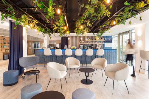 a room with chairs and a bar in the background at Holiday Inn Express Paris-Canal De La Villette, an IHG Hotel in Paris