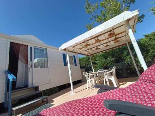 a patio with a table and chairs under a canopy at Mobil home 6 personnes climatisation Sainte Croix du Verdon - Gorges du Verdon in Sainte-Croix-de-Verdon