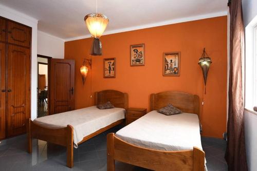 two beds in a room with orange walls at Villa Paraiso in Lagoa