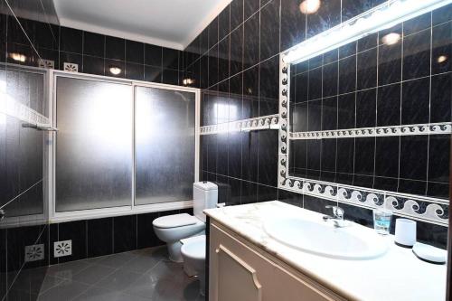 a bathroom with a toilet and a sink and a mirror at Villa Paraiso in Lagoa