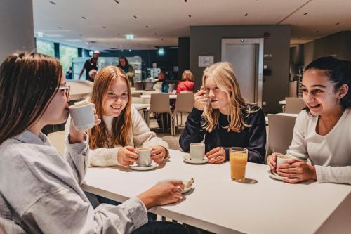 Un grupo de mujeres sentadas en una mesa tomando café. en Jugendherberge München City, en Múnich