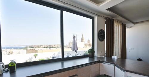 a room with a large window with a view of the city at Millennium Penthouse with private Hot Tub Gozo in Għajnsielem