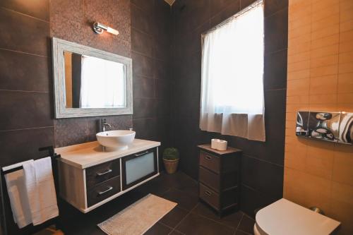 a bathroom with a sink and a toilet and a window at Millennium Penthouse with private Hot Tub Gozo in Għajnsielem