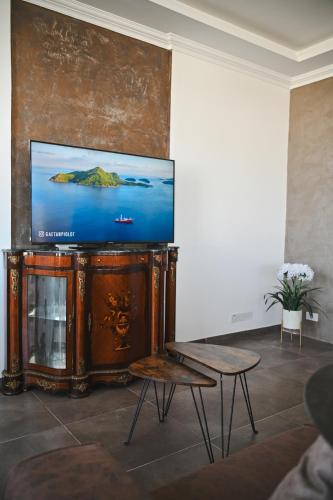 a living room with a flat screen tv on a stand at Millennium Penthouse with private Hot Tub Gozo in Għajnsielem