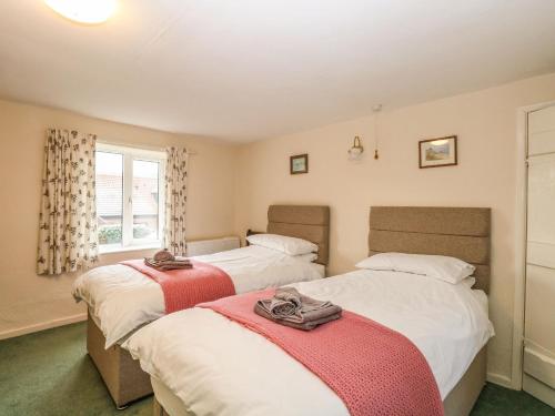 a bedroom with two beds and a window at Primrose Cottage in Wells next the Sea