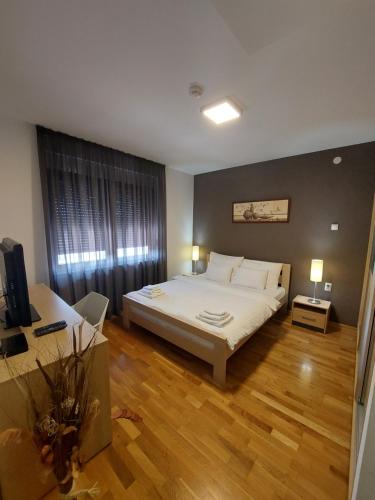 a bedroom with a large white bed and wooden floors at Motel MS in Srpski Itebej