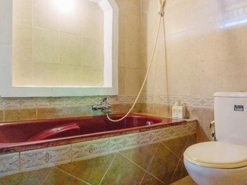 ein Badezimmer mit einer roten Badewanne und einem WC in der Unterkunft Artini 2 Cottage Ubud in Ubud