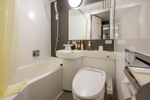 a bathroom with a toilet and a sink and a mirror at Kagoshima Plaza Hotel Tenmonkan in Kagoshima