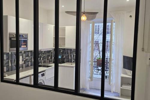 une cuisine avec des fenêtres à cadre noir et une cuisine avec des appareils électroménagers blancs dans l'établissement Lafayette appartement, à Paris