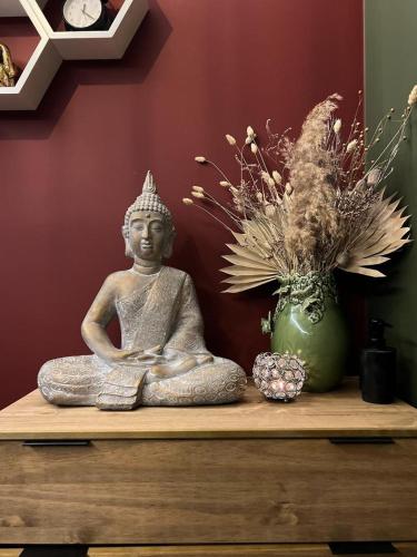 a statue sitting on a table with a vase of flowers at Seven Hotel Bytom - Katowice in Bytom
