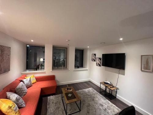 ein Wohnzimmer mit einem roten Sofa und einem Flachbild-TV in der Unterkunft Spacious Sleep 8 Flat 20 mins Central London BP9 in London
