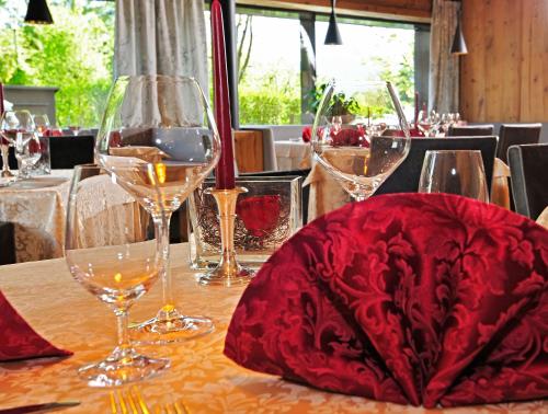 a table with wine glasses and a red hat on it at Hotel Restaurant Kirchsteiger in Vollan