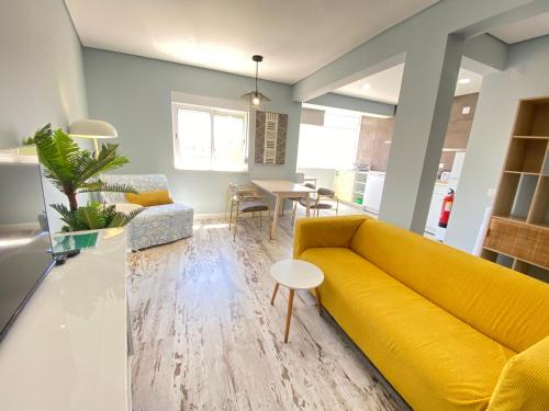 a living room with a yellow couch and a table at Apartamento Gertrudes in Setúbal