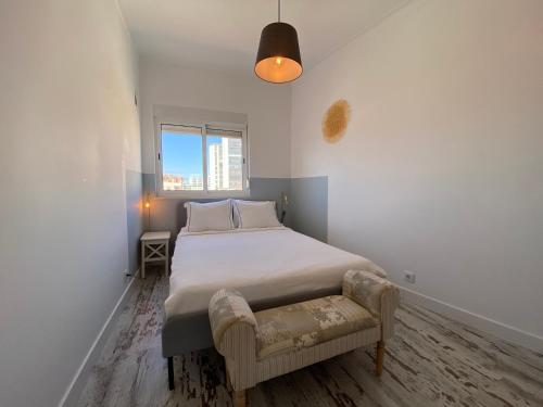 a small bedroom with a bed and a chair at Apartamento Gertrudes in Setúbal