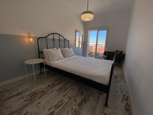 a bedroom with a bed and a table and a window at Apartamento Gertrudes in Setúbal