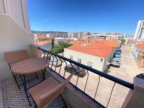 a balcony with two chairs and a view of a city at Apartamento Gertrudes in Setúbal