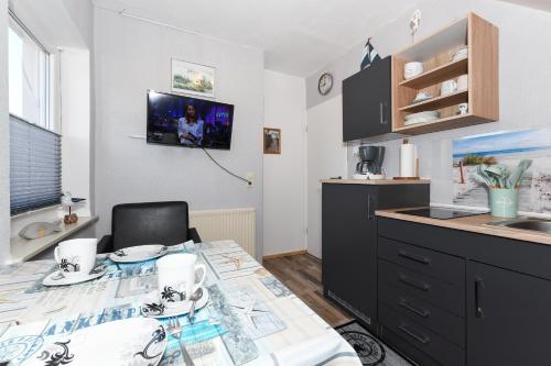 Una cocina con una mesa, un fregadero y una encimera. en Ferienwohnung Ankerplatz im Gästehaus Kock, en Neuharlingersiel