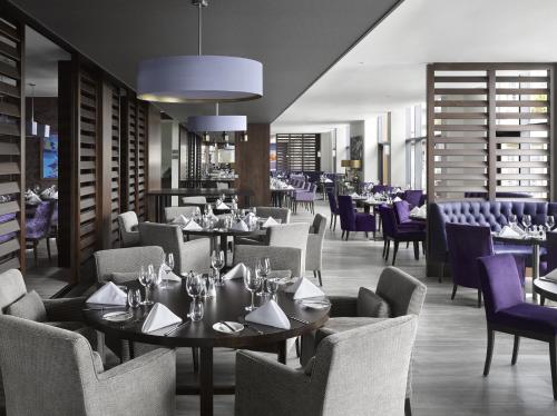 a restaurant with tables and chairs and purple chairs at Radisson Blu Waterfront Hotel, Jersey in Saint Helier Jersey