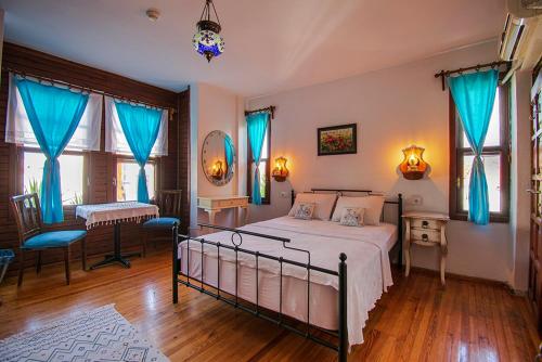 シアジクにあるSığacık Nossa Casa Pansiyonのベッドルーム1室(ベッド1台、テーブル、青いカーテン付)
