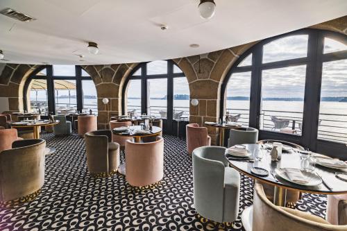 a restaurant with tables and chairs and windows at Castelbrac Hotel & Spa in Dinard