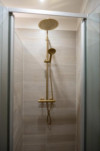 La salle de bains est pourvue d'une douche et d'un ventilateur mural. dans l'établissement La perle du Marais, à Paris