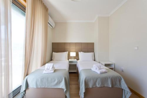 two twin beds in a room with a window at Studios Porto Solar in Porto