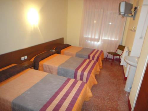 a hotel room with three beds and a sink at Pensió Restaurant Llança in Llança