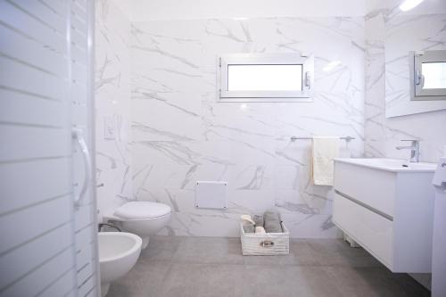 a white bathroom with a toilet and a sink at Villa Antonietta in Carovigno