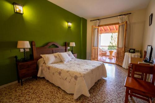 een slaapkamer met een bed met een groene muur bij Hotel Rural Familiar Almirez-Alpujarra in Laujar de Andarax