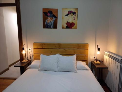 sypialnia z łóżkiem i dwoma obrazami na ścianie w obiekcie Apartamento Ábside de San Juan I w mieście Estella