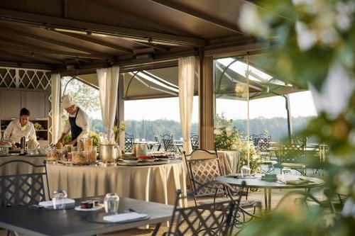 a restaurant with two chefs preparing food on tables at COMO Castello Del Nero in Tavarnelle Val di Pesa