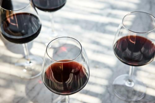 three glasses of red wine sitting on a table at COMO Castello Del Nero in Tavarnelle in Val di Pesa