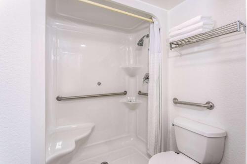 y baño blanco con aseo y ducha. en Ramada by Wyndham Altamonte Springs Near I-4 en Orlando
