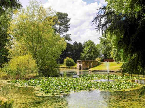 a garden with a fountain in the middle of a pond at Mercure Shrewsbury Albrighton Hall Hotel & Spa in Shrewsbury