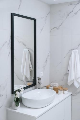 a white bathroom with a sink and a mirror at Athena Home South Crete in Kapparianá