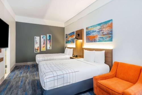 a hotel room with two beds and a chair at La Quinta by Wyndham St. George in St. George