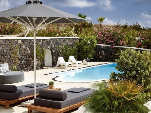a pool with two lounge chairs and an umbrella at Modern and Comfortable Santorini Villa 3 Bedrooms Villa Aqua Private Pool and Beautiful Outdoor Space Exo Gialos in Karterados